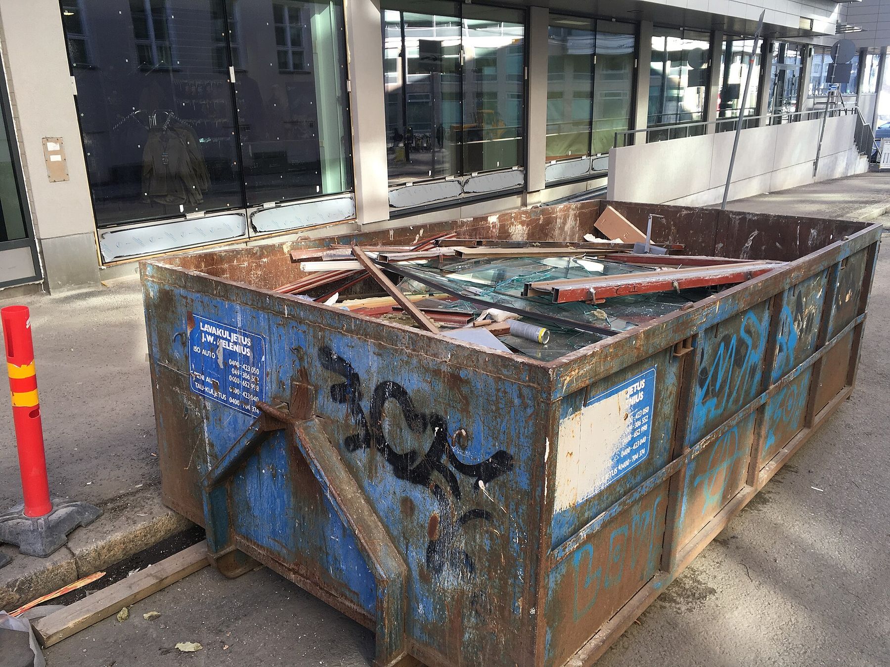 A dumpster filled with lumber, glass, and other junk from a cleanout