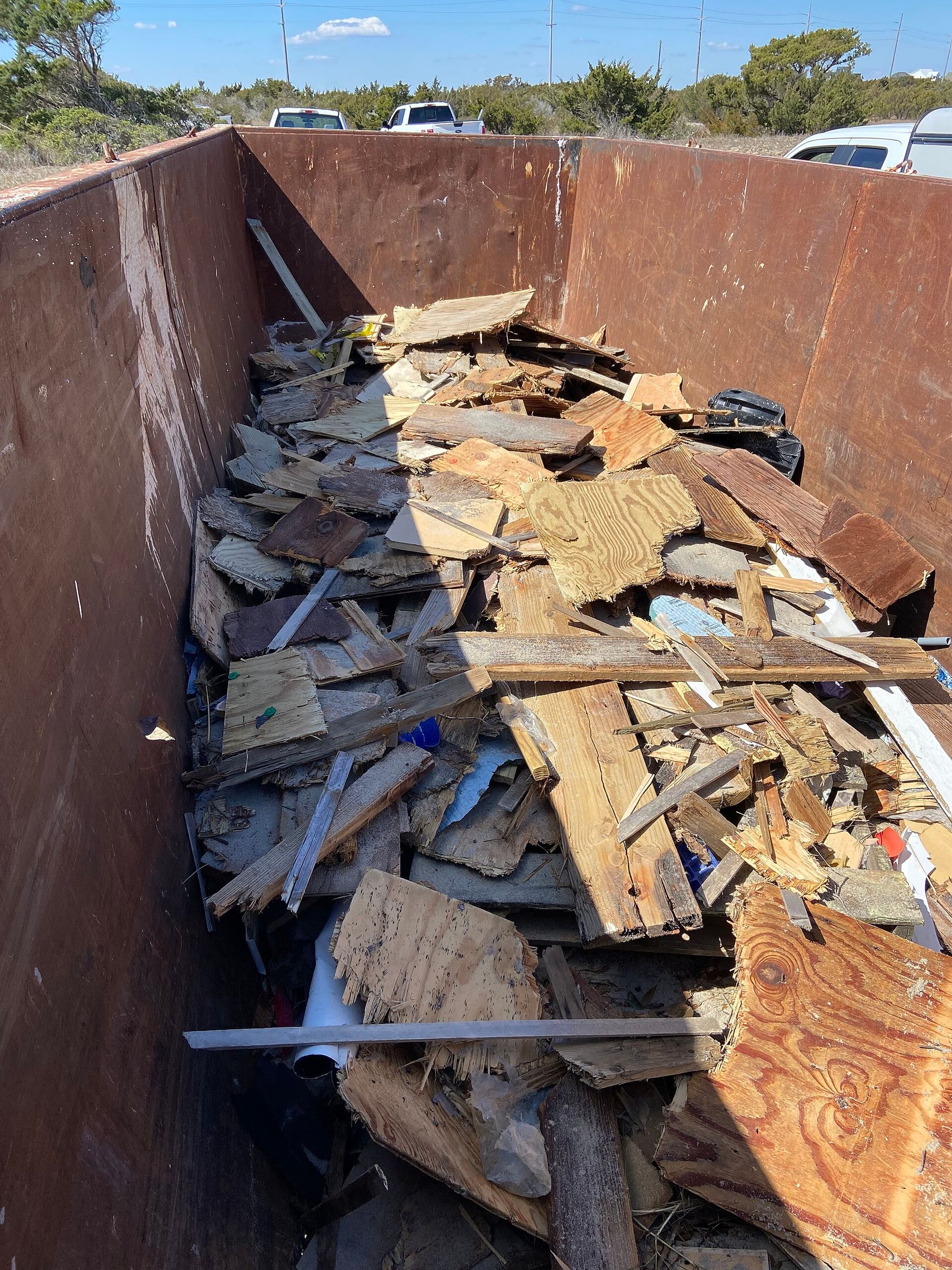 A dumpster loaded with wood and mixed debris from a property cleanout