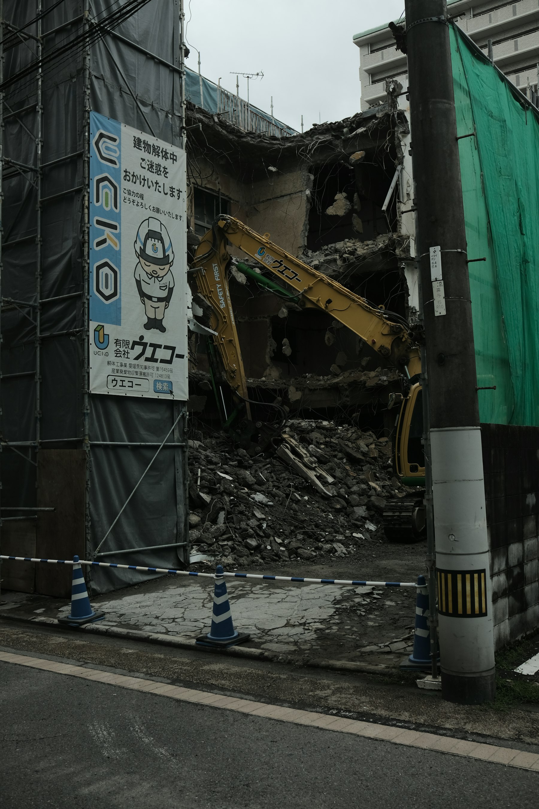 Excavator clearing a building during demolition, with rubble on the ground